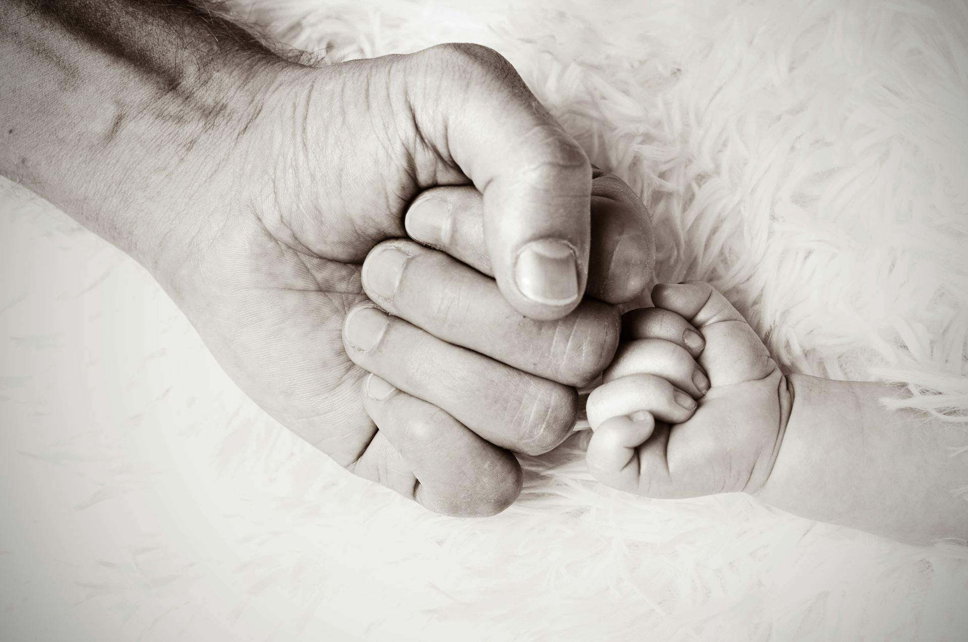 Mans hand and babys hand touching